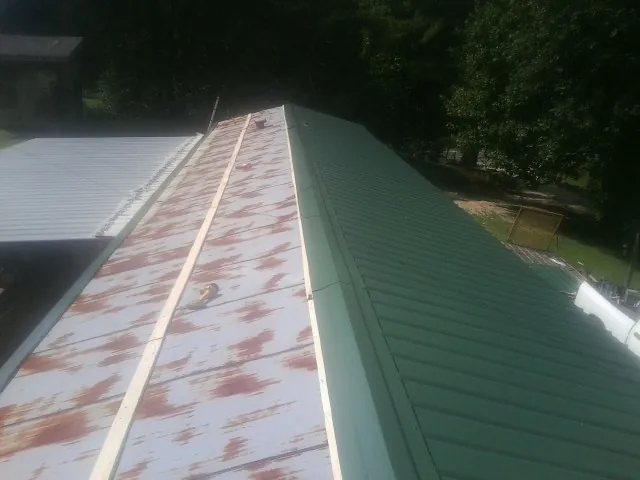 Old rusted panels beside newly installed green metal roofing — Wind Damage Roof Repair by Roofing Brothers in Hadley